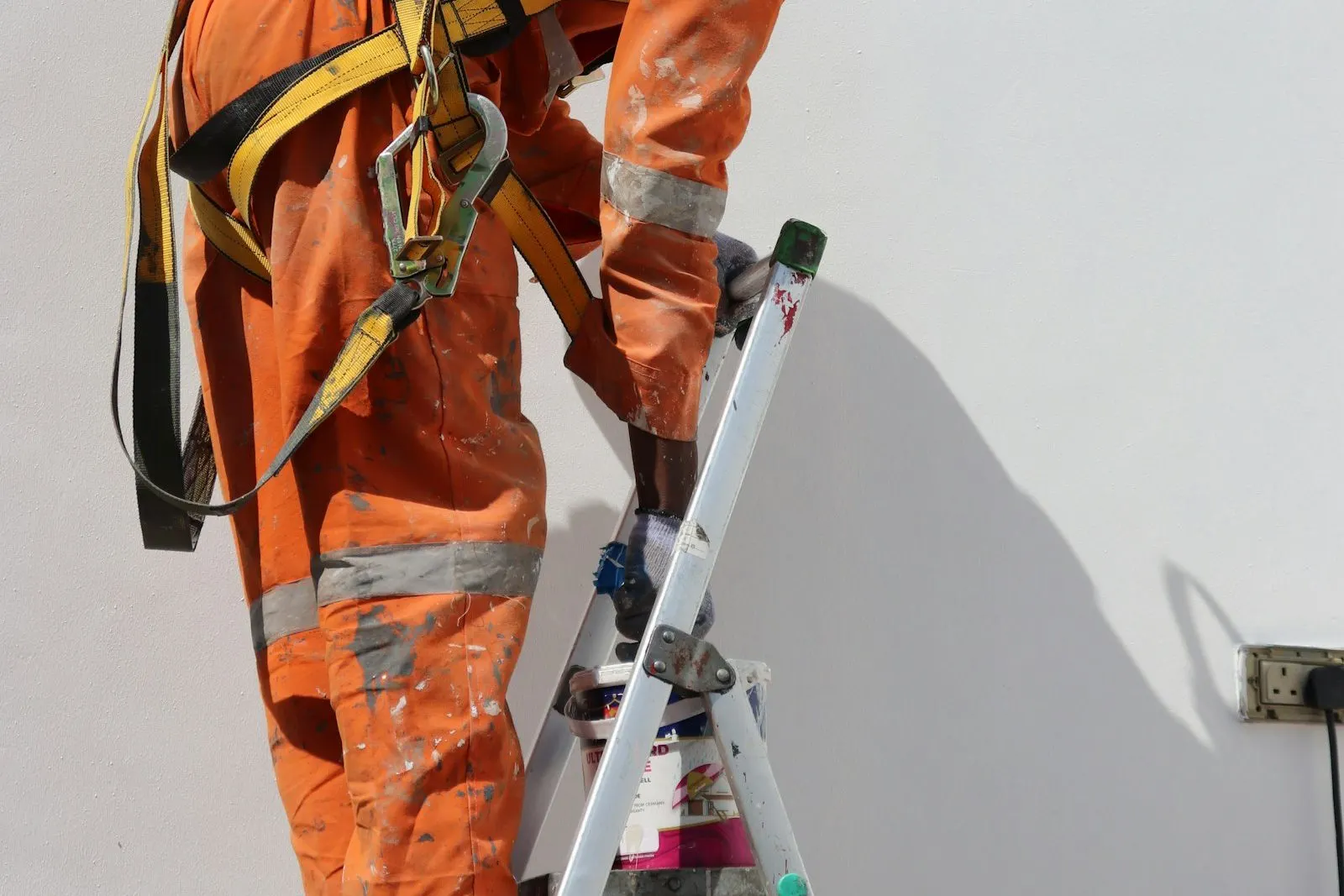 Trabajador con arnés subiendo una escalera